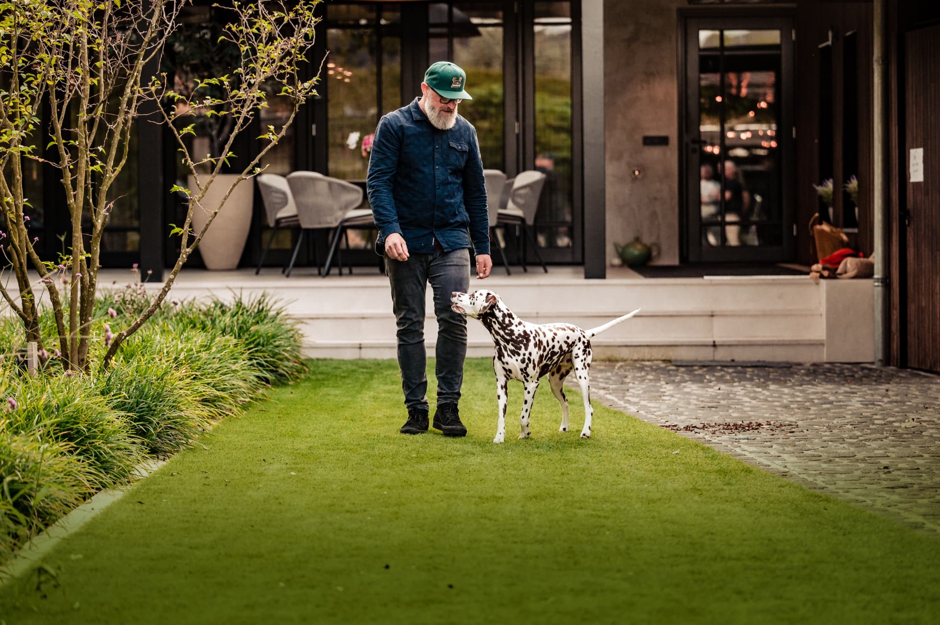Man met hond op een kunstgrasgazon in de achtertuin
